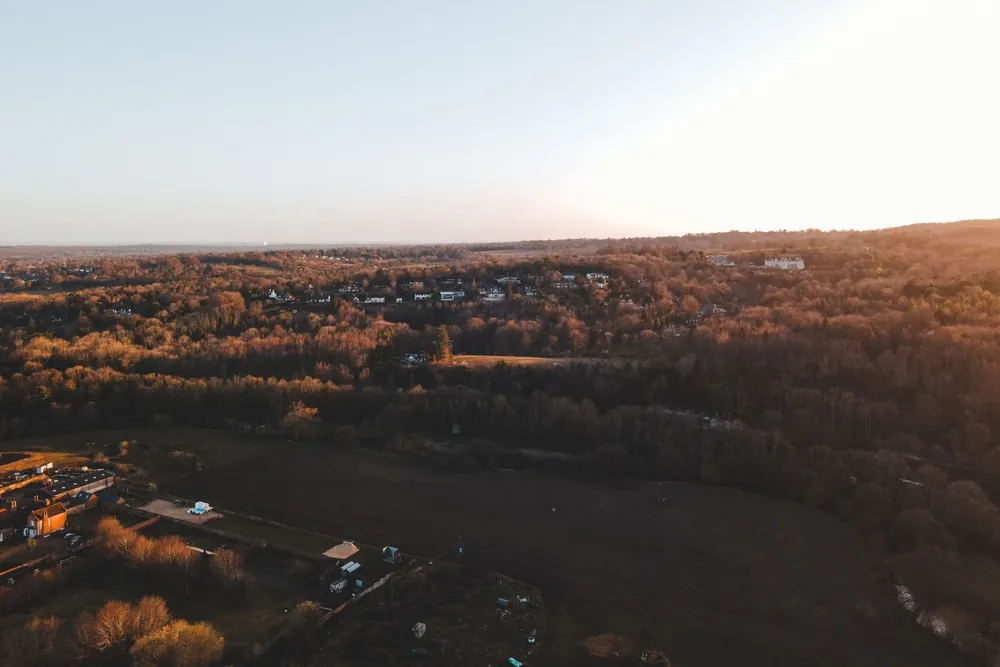 Campagne anglaise vallonnée avec maisons et forêts au coucher du soleil