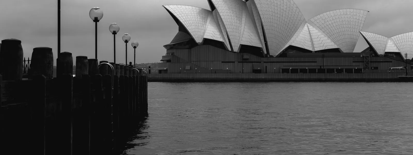 Façade géométrique de l'Opéra de Sydney sous un ciel nuageux