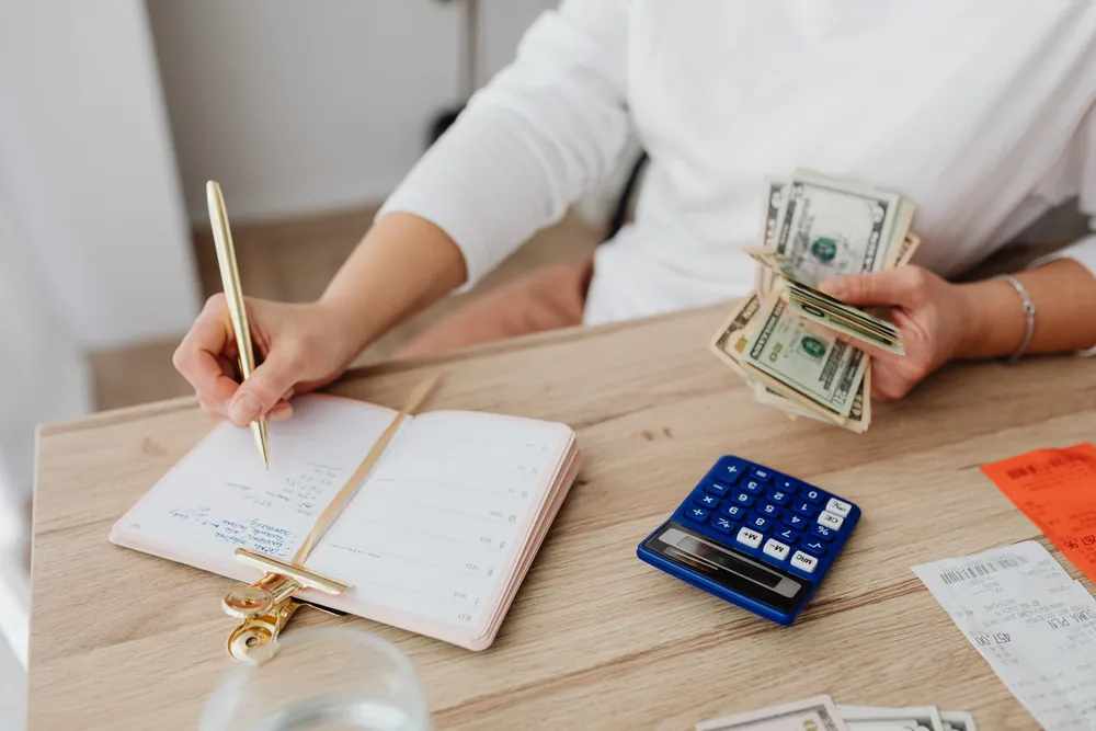 Personne calculant son budget avec des billets et un agenda