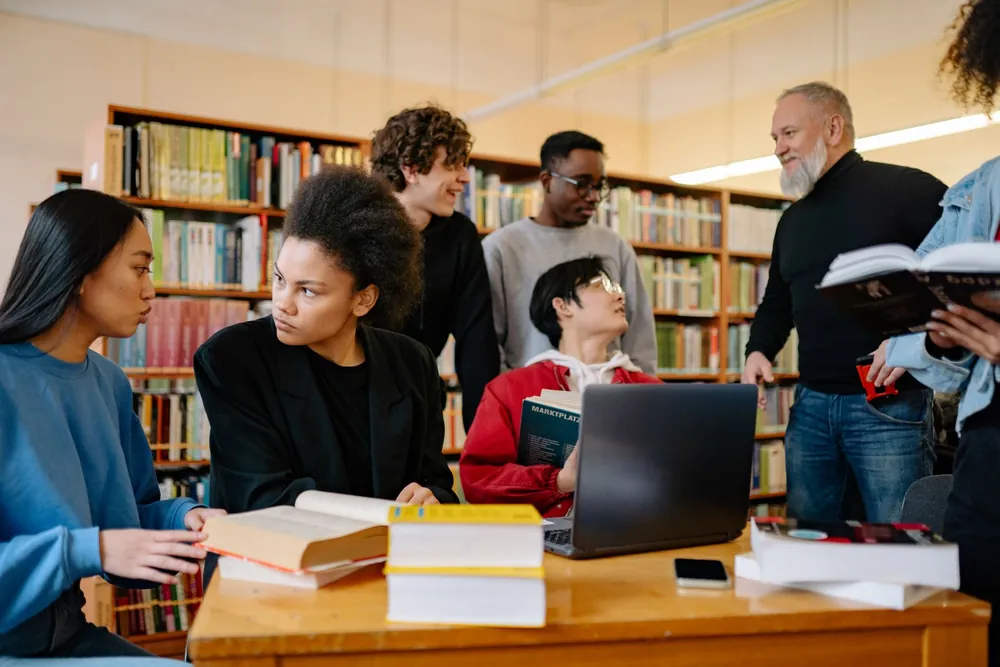 Groupe d'étudiants échangeant autour de leurs révisions en bibliothèque