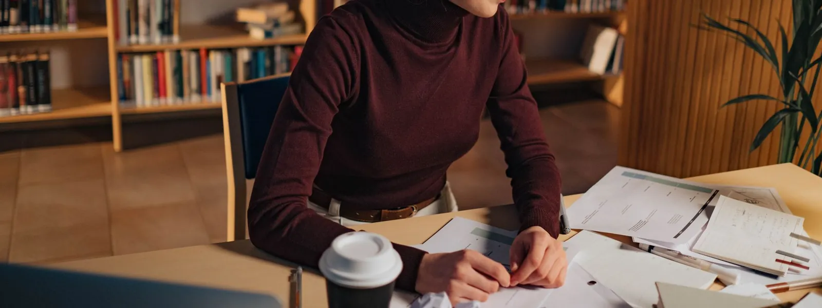 Étudiante concentrée sur ses documents dans une bibliothèque universitaire