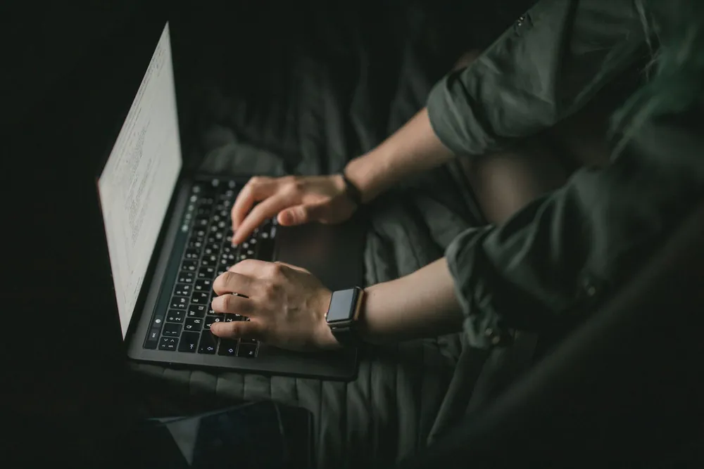 Mains tapant sur un clavier d'ordinateur portable pour rédiger un CV