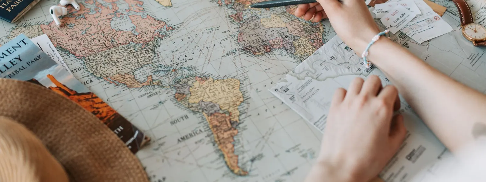 Mains pointant des destinations sur une carte du monde avec passeport