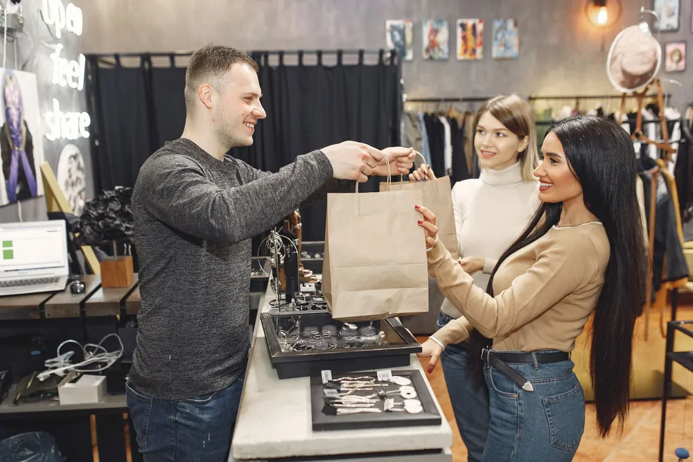 Un vendeur remet un sac d'achats à une cliente satisfaite en boutique