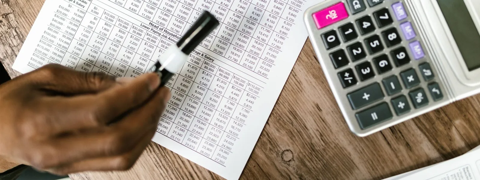 Des documents fiscaux et une calculatrice posés sur un bureau en bois
