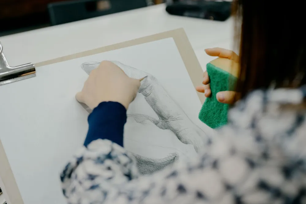 Un étudiant en art dessine soigneusement une main dans un atelier