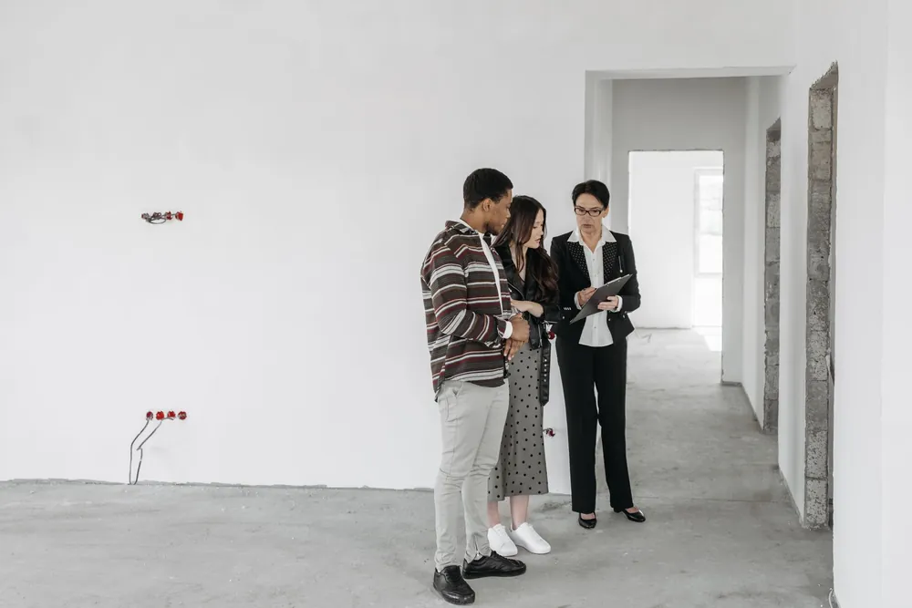 Agent immobilier échangeant avec un couple dans un logement en travaux