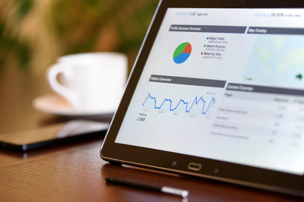 Tablette affichant des graphiques d'analyse marketing sur un bureau en bois