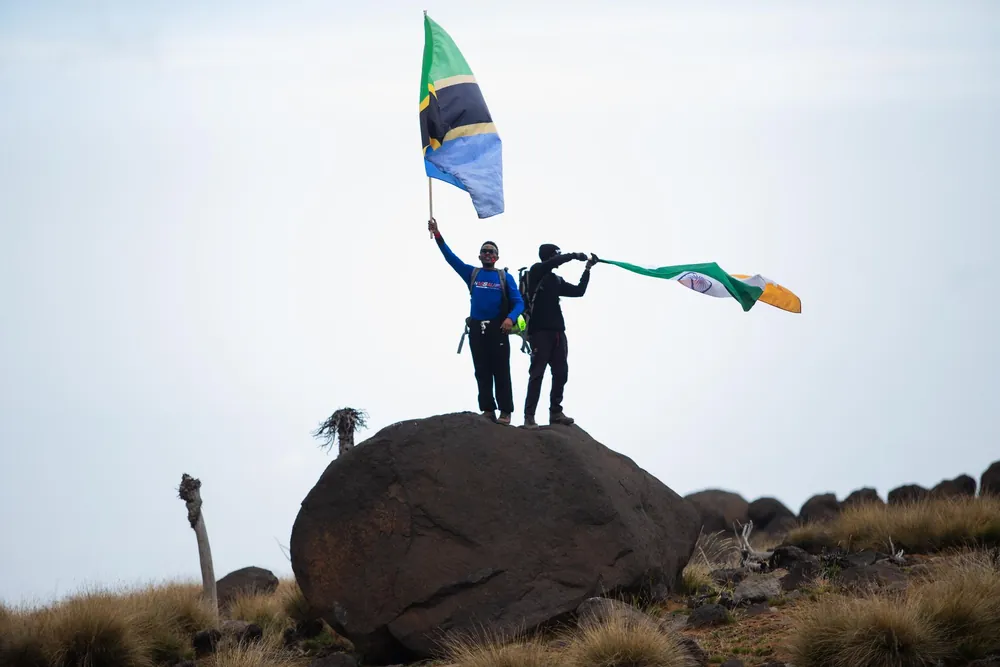 Deux personnes brandissant des drapeaux au sommet d'une montagne