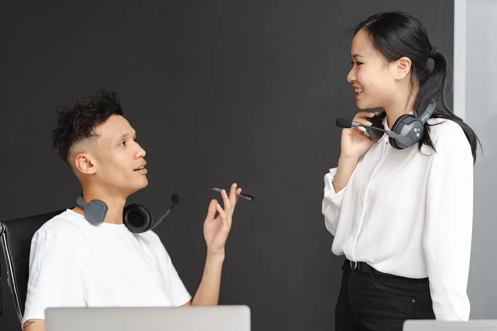 Deux collègues échangeant avec un casque dans un bureau moderne