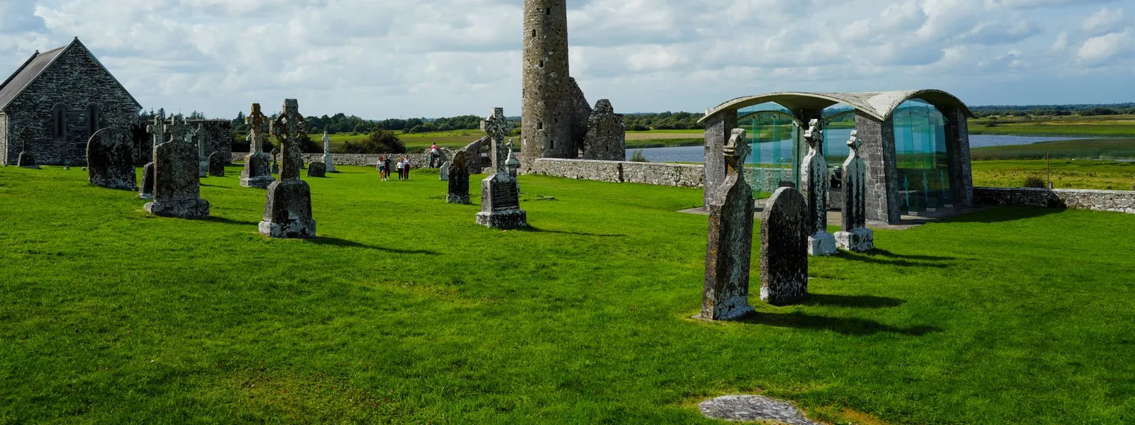 Une tour ronde se dresse dans un ancien cimetière irlandais entouré de verdure