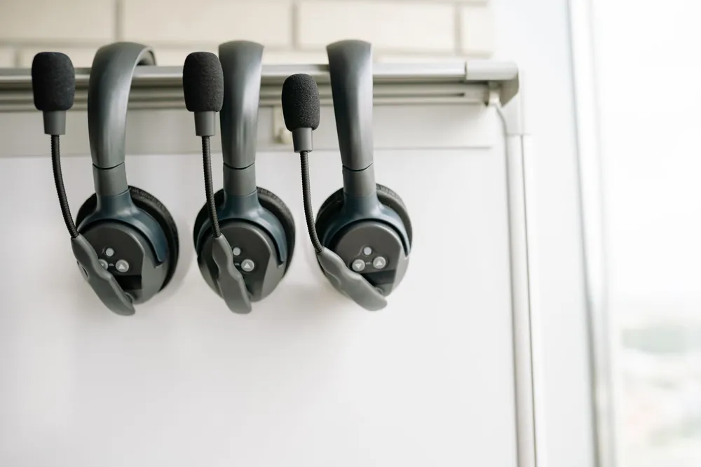 Casques d'interprétation alignés sur un support, symbole de la traduction simultanée