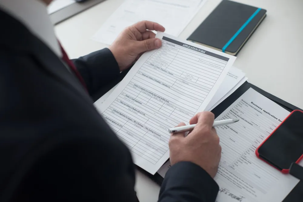 Recruteur en costume examinant un dossier de candidature imprimé