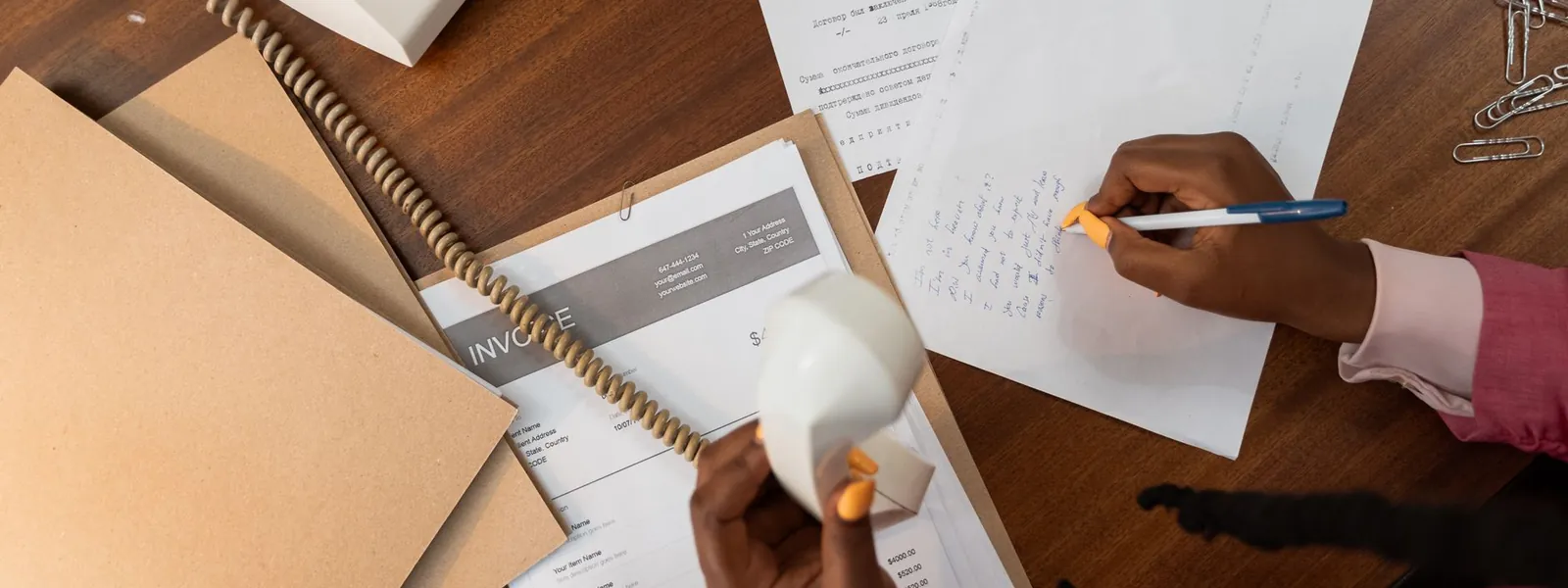 Personne rédigeant des notes sur un bureau en bois pour une lettre de motivation