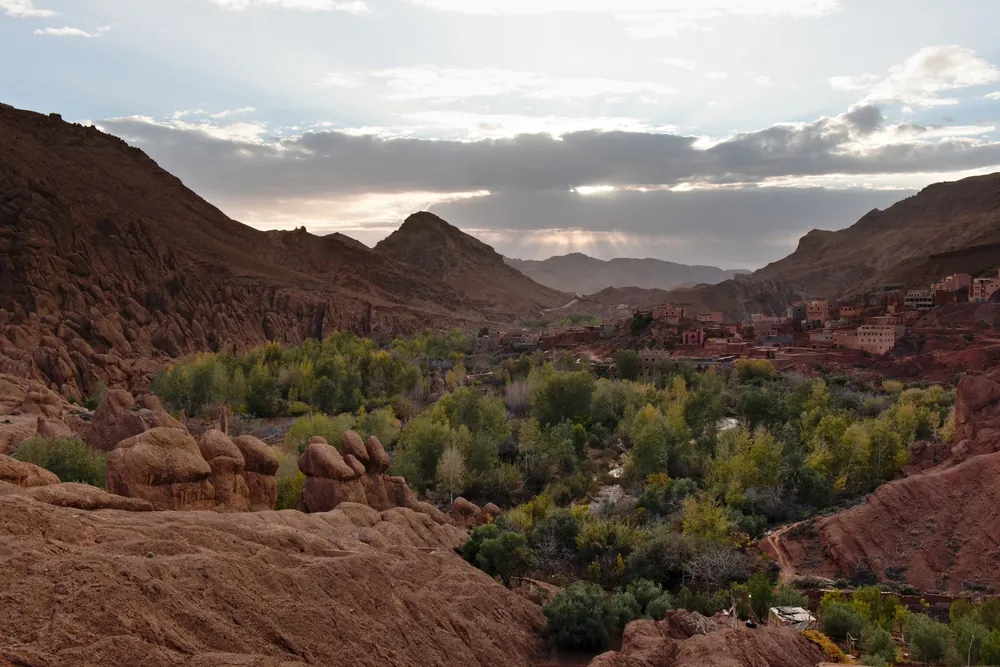 Vallée marocaine verdoyante entourée de montagnes rocheuses au crépuscule