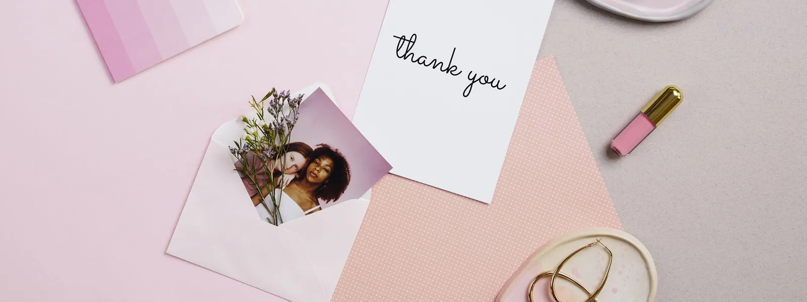 Carte de remerciement entourée d'accessoires roses sur une table