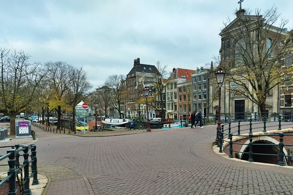 Pont pavé sur un canal amstellodamois bordé d'architecture hollandaise