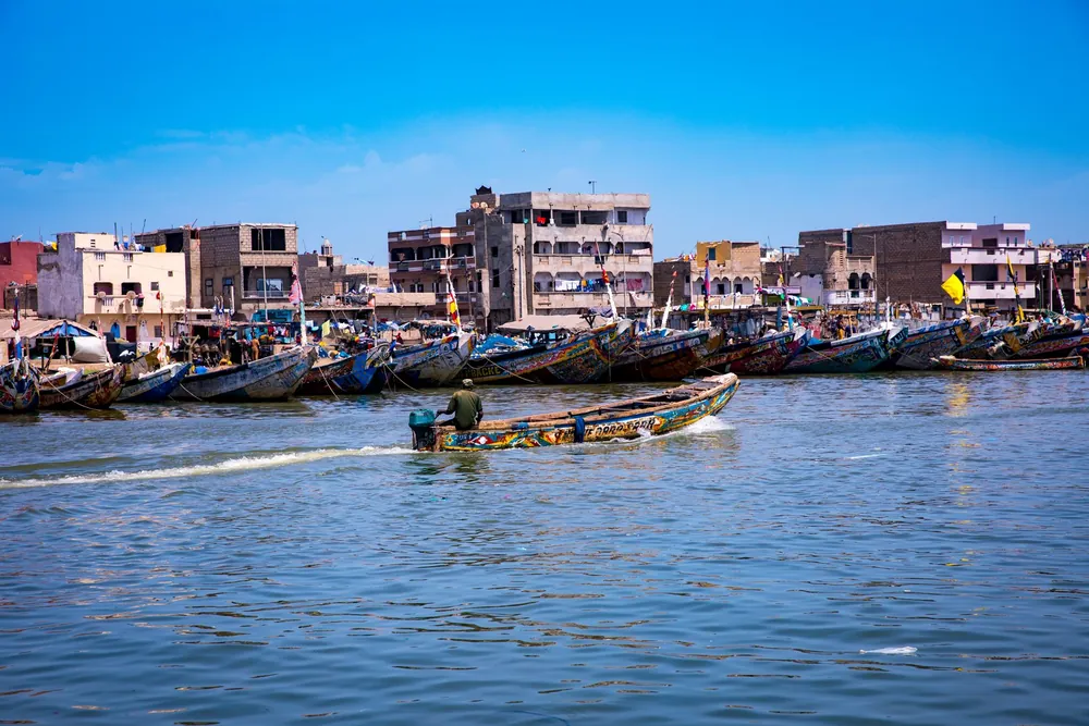 Bateaux de pêche colorés alignés le long d'un village côtier sénégalais