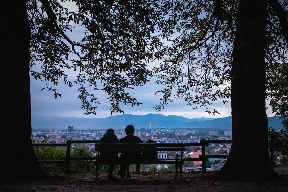 Couple assis sur un banc surplombant les toits de Ljubljana