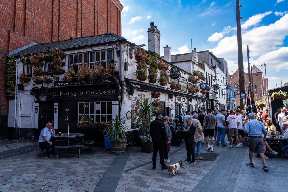 Des passants se rassemblent devant un pub historique de Belfast un jour ensoleillé