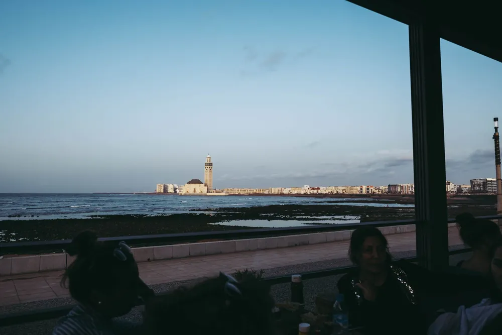 Mosquée Hassan II vue depuis le littoral de Casablanca avec un café au premier plan