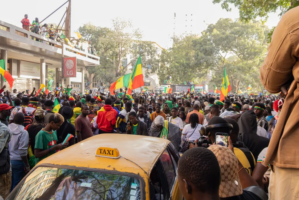 Foule animée dans une rue de Dakar lors d'une célébration avec des drapeaux