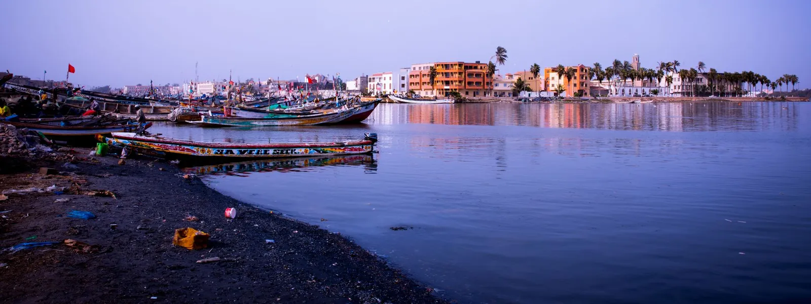 Bateaux amarrés près de la côte de Dakar avec bâtiments colorés au loin