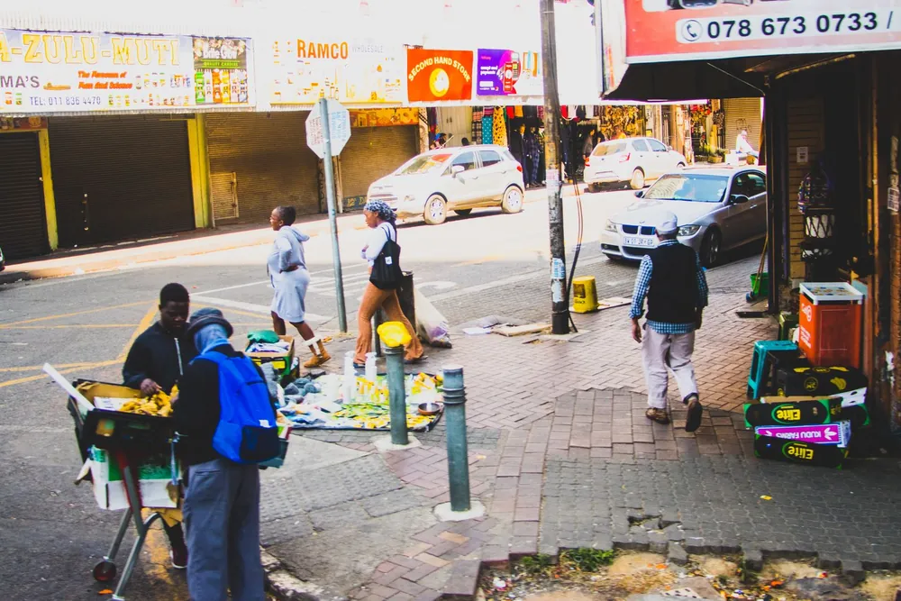 Coin de rue animé à Johannesburg avec passants, voitures et étals de marché