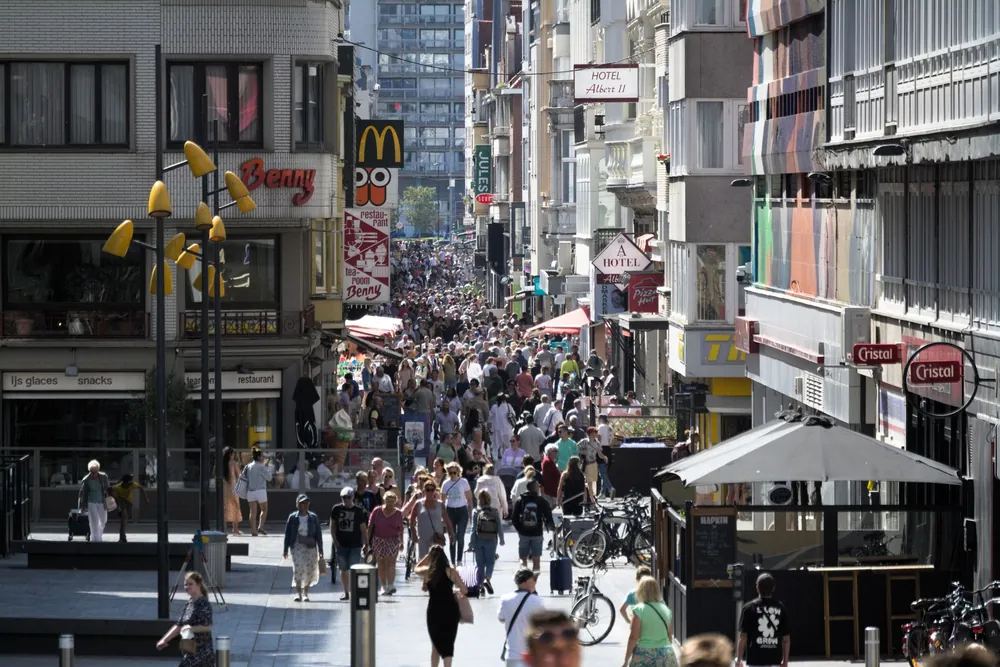 Rue commerçante animée bordée de commerces et de passants en Belgique