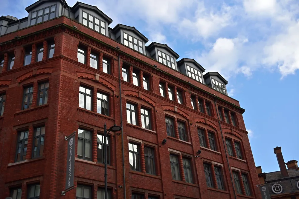 Façade en briques rouges typique de Manchester se détachant sur un ciel bleu