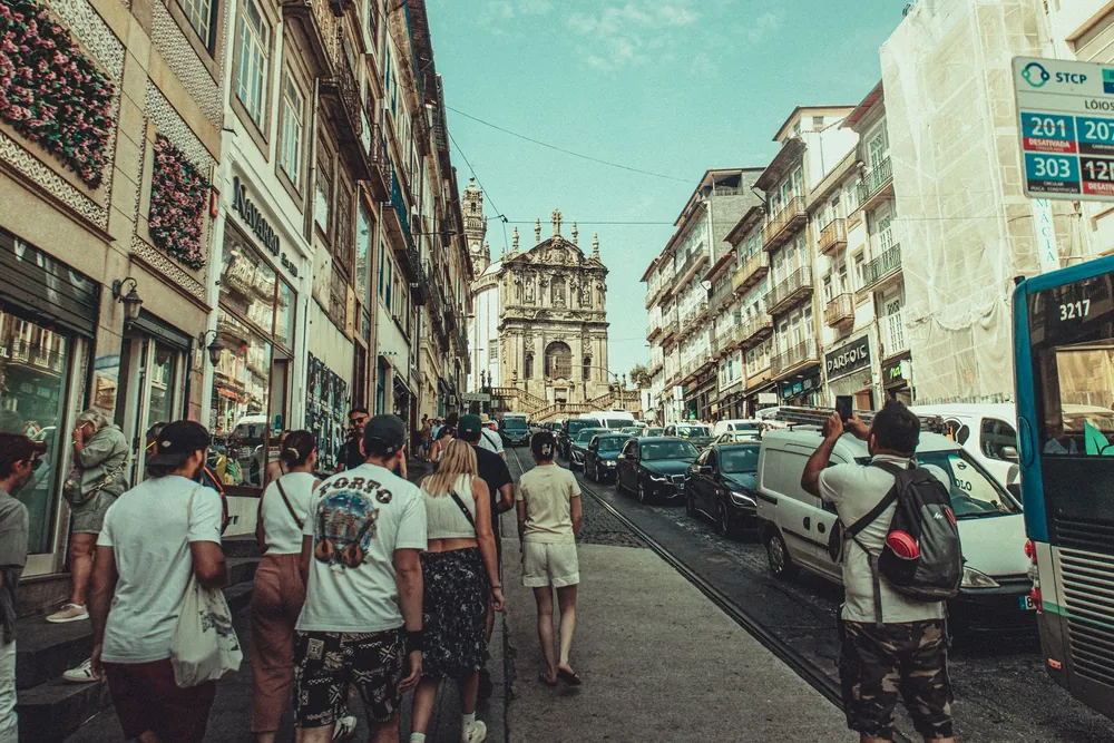 Rue touristique de Porto animée sous un ciel bleu bordée d'architecture classique