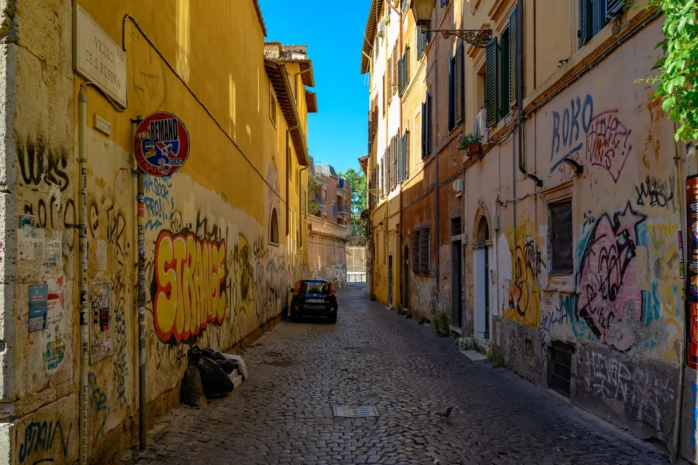 Ruelle pavée du centre historique de Rome ornée de street art coloré