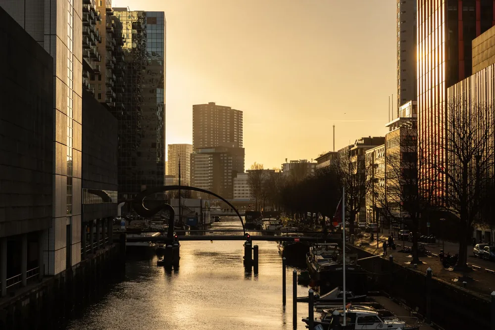 Canal de Rotterdam au coucher de soleil reflétant l'architecture moderne de la ville