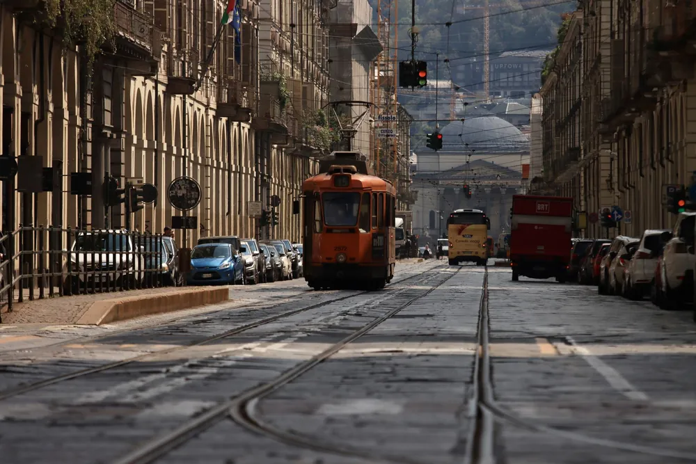 Tramway ancien circulant dans une rue bordée de bâtiments historiques à Turin