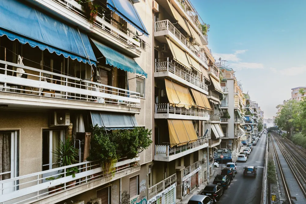 Des immeubles résidentiels bordent une rue calme et une voie ferrée à Athènes