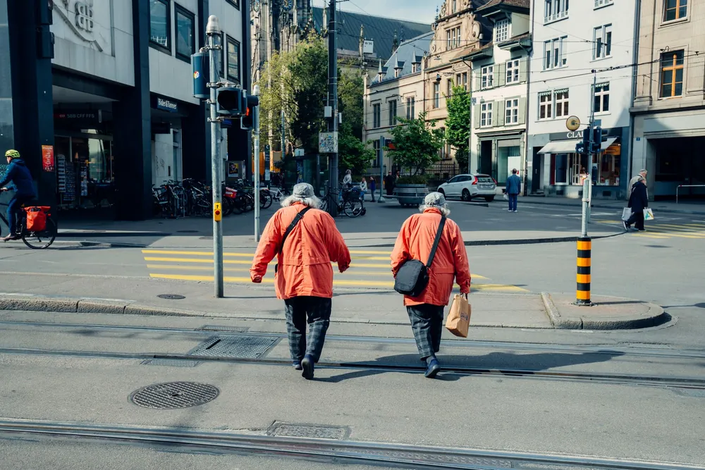 Couple âgé en veste rouge traversant une rue animée de Bâle