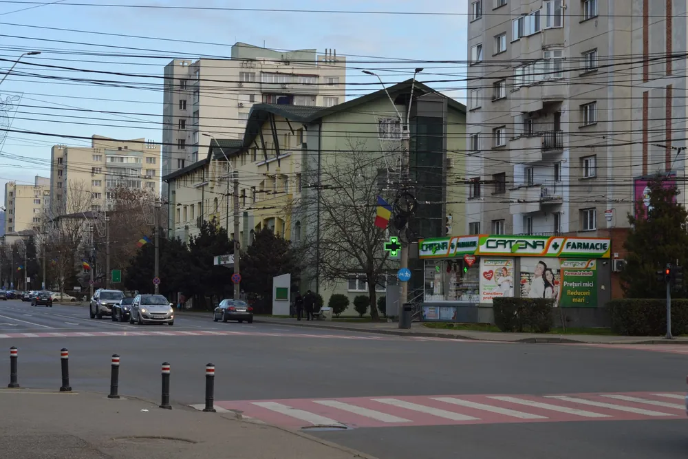 Rue animée de Bucarest bordée d'immeubles et d'une pharmacie