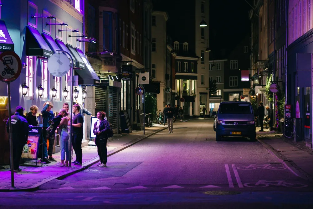 Rue animée de Copenhague la nuit éclairée par des lumières violettes