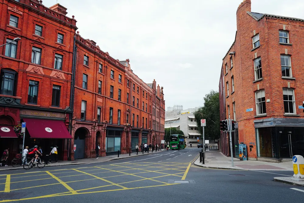 Rue animée de Dublin bordée de façades en briques rouges et bus vert