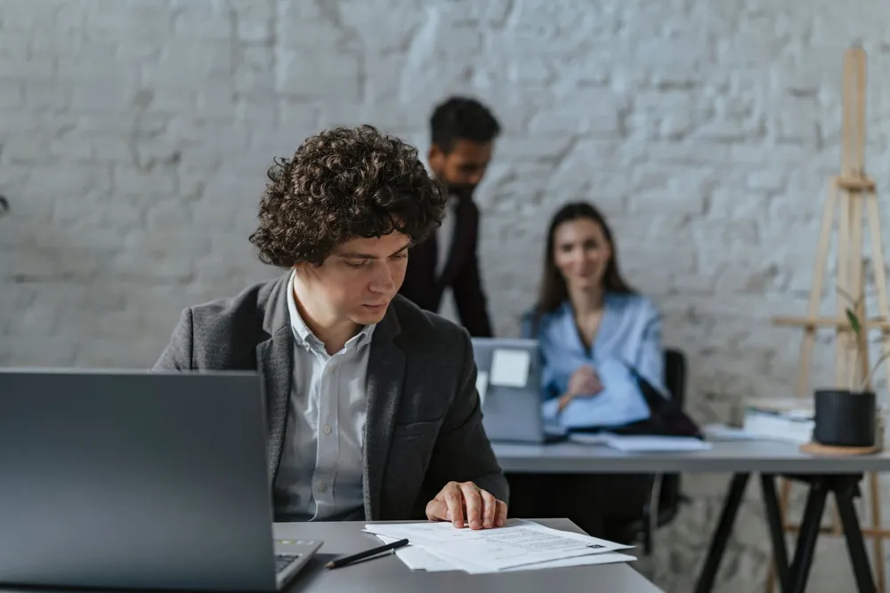 Jeune stagiaire concentré en train d'examiner des documents au bureau
