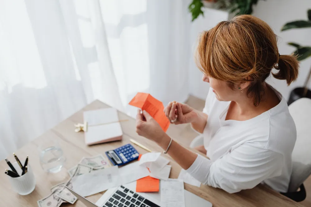Femme organisant ses finances avec factures et calculatrice à domicile