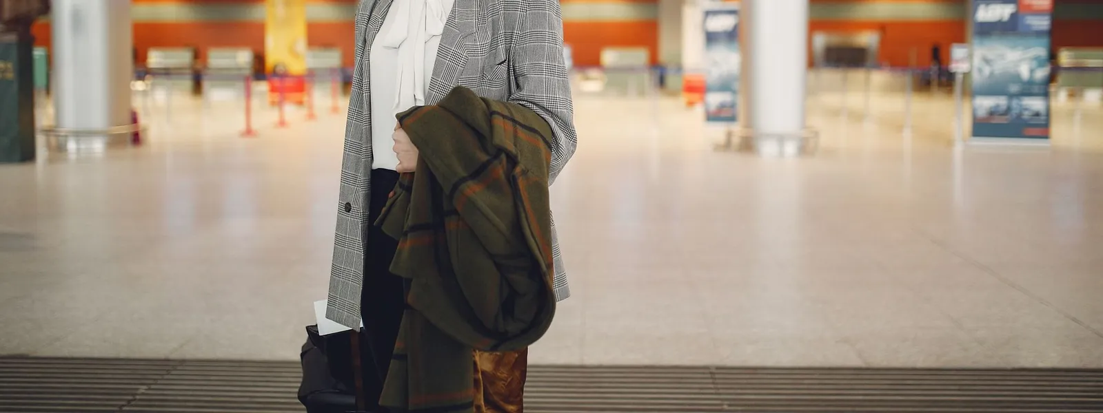 Femme d'affaires consultant les vols dans un aéroport avec sa valise
