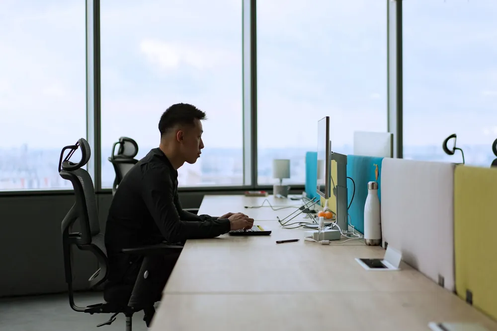 Expatrié travaillant sur ordinateur dans un bureau lumineux et moderne